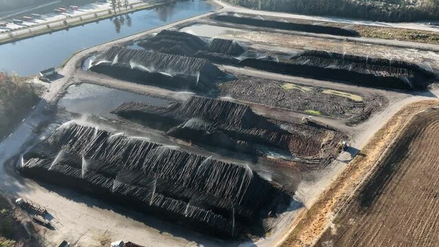 Tree logs receiving water irrigation in a paper mill before they become pulp.