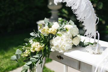 Close up of a table decorated with fresh white and yellow flowers for painting the newlyweds against the backdrop of the arch. Wedding concept
