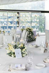  Wedding decorations. Served wedding table with decorative fresh white flowers and candles. Celebration details. flower composition roses plates and candles in candlesticks