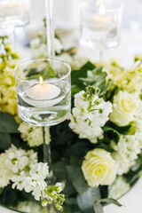 Obraz na płótnie Canvas Close up of a wedding table decoration with white flowers and candles. Wedding floristic concept