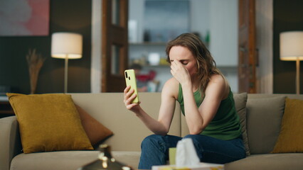 Crying lady talking smartphone on home sofa. Unhappy girl cellphone video call