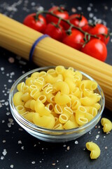 Pasta lies in a glass plate on a black background.