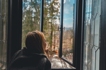 A Serene View: Woman Gazing at Forest Through Window at Peles Castle