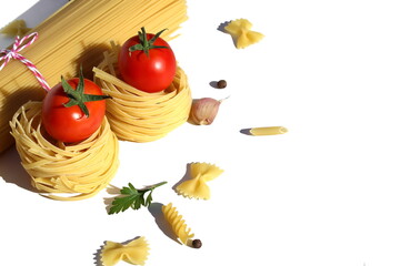 Knitted spaghetti lies on a white background with pasta nests and tomatoes.