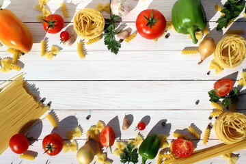 On a white wooden background there are different types of pasta with tomatoes and herbs with space for text.	