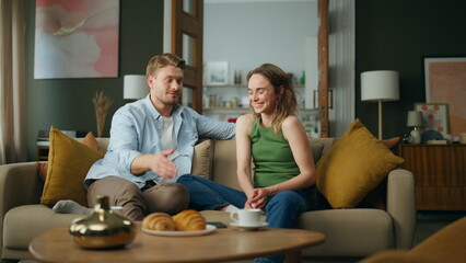 Excited spouses laughing sofa interior. Happy smiling family having fun at home