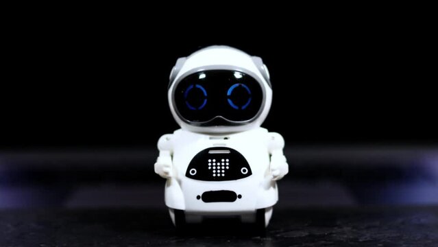 Real white small Robot on black table with flickering eyes. Futuristic future technology. Business helper for development.