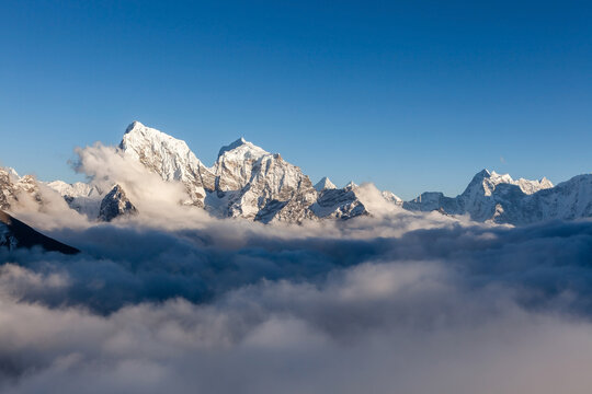 Snowy himlayan peaks in the sea of clouds. Beautiful landcape in Nepal on Everest Base Camp trek.