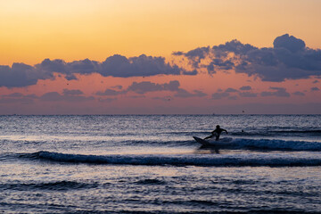 Obraz premium 日の出の中サーフィンをする人