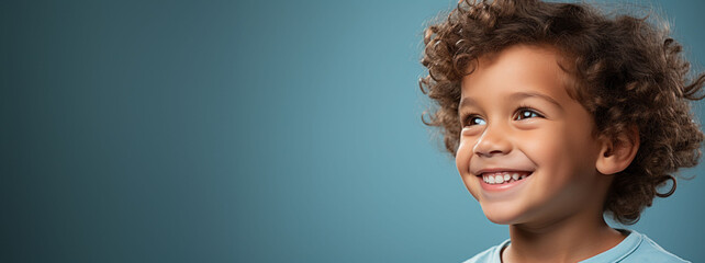 Joyful child with curly hair smiling, representing health and happiness with a banner area for text on dental care themes.