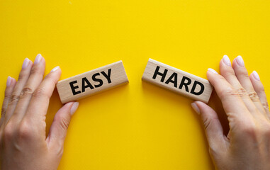 Easy or Hard symbol. Concept word Easy or Hard on wooden blocks. Businessman hand. Beautiful yellow...