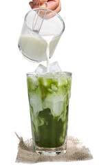 Homemade ice matcha latte green tea. A hand pouring white creamy milk into long glass of matcha...