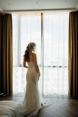 a beautiful, delicate and sexy blonde bride in a veil by the window