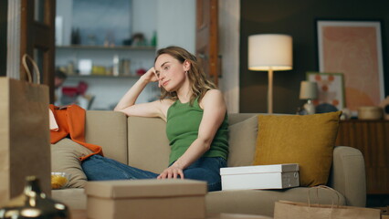 Nervous lady sitting sofa waiting parcel at home. Stressed woman tapping fingers