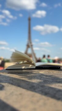 Wind Flipping Notebook Pages Eiffel tower on background
