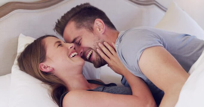 Laugh, love and couple cuddle in bed in morning for bonding together in modern apartment. Smile, care and young man and woman laying, resting and relaxing in bedroom for marriage on weekend at home.