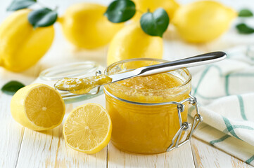 Sweet lemon jam in jar with juicy lemon slices on wooden table. Delicious homemade natural lemon jam.