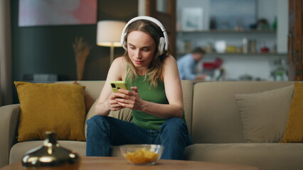 Headphones woman reading telephone home. Student listening educational podcast