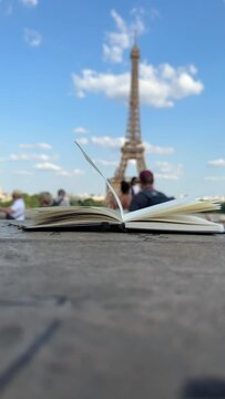 Wind Flipping Notebook Pages Eiffel tower on background