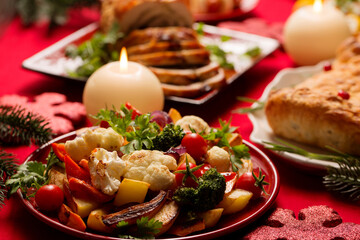 Warm salad of cooked vegetables on a red plate