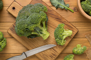 Fresh tasty broccoli on wooden background, top view