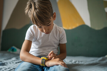 caucasian boy 7 years old male child kid use smart watch at home - obrazy, fototapety, plakaty