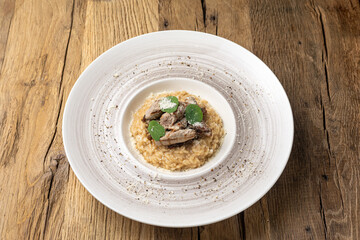 Risotto with lamb fillet on a wooden table.
