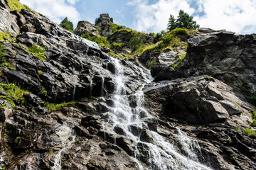 Fototapeta na wymiar Capra waterfall also known as Iezerului waterfall, located on the southern slope of the Făgăras Mountains, right next to Transfagarasan, between Cabra Capra and Balea Lake, on DN7C. Romania.