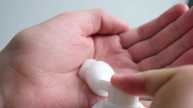 Teenage boy with acne problem pumping foam into his hand close-up