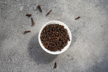 clove spices in a ceramic bowl on a gray background, no people, top view, minimalism
