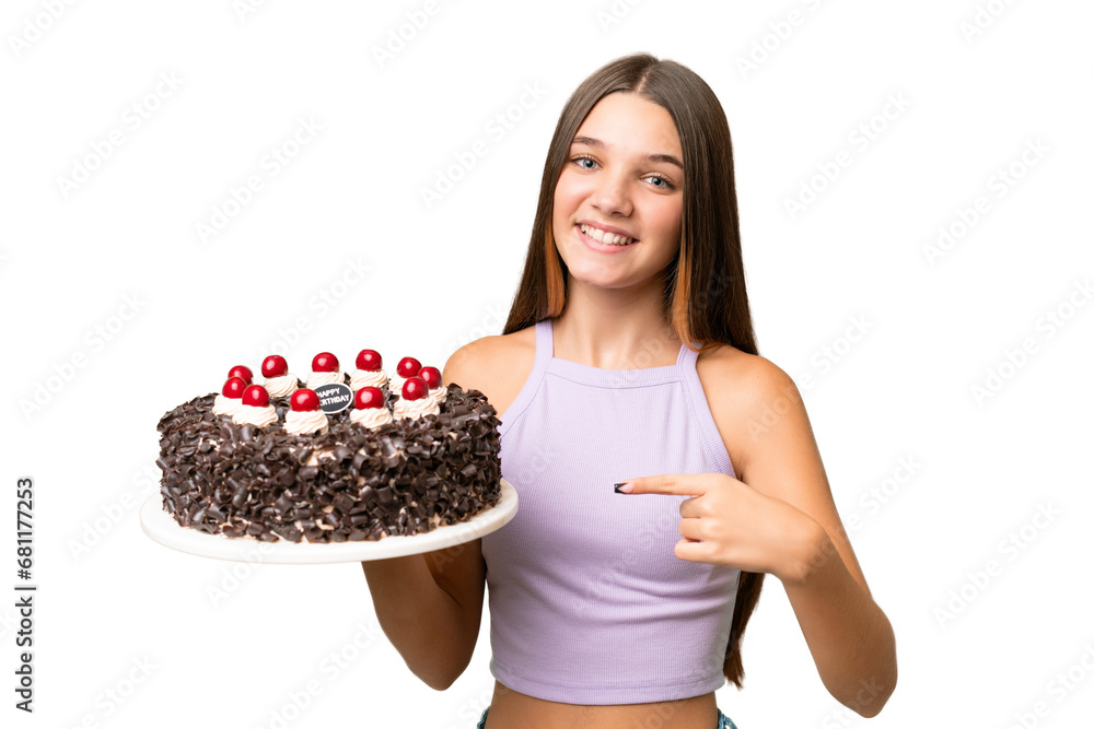 Sticker Teenager caucasian girl holding birthday cake over isolated background and pointing it