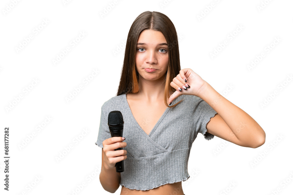 Sticker Teenager singer girl picking up a microphone over isolated background showing thumb down with negative expression