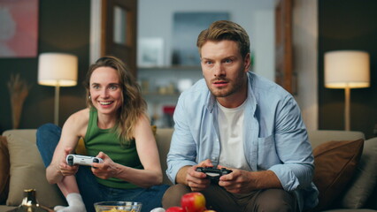 Excited couple competing videogame at home. Nasty man taking gamepad from woman