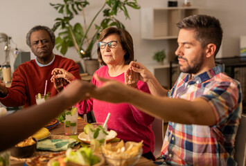 Catholic family adult that prays before eating at home