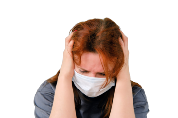 A redhead woman with a flu virus in a medical mask holds on to her head, closeup, isolated on a white background. Woman with a sore head sits on the bed