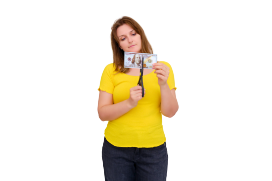 A woman in an empty house cuts dollars, isolated on a white background. The concept of wasted money, taxes and difficulty paying for housing.