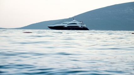 Luxurious motor yacht swimming through calm sea waves at sunset. Holiday, summer vacation and tourism
