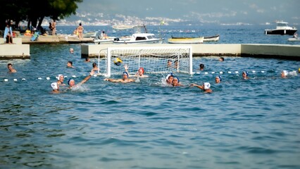 Male water polo team having game in open sea water. July, 2023, Kotor, Montenegro.