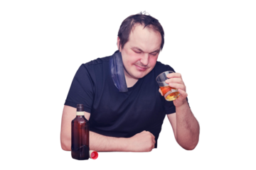 A man looks thoughtfully at a glass of whiskey sitting in a home kitchen, isolated on a white background. Problems with drinking alcohol during a pandemic, isolation and lockdown