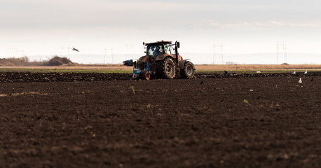 Fototapeta premium Tractor on the field during sunset.