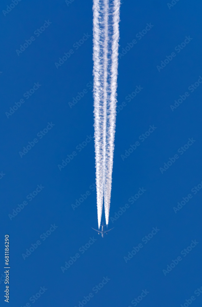 Wall mural passenger jet in flight leaving a wide distinct contrail