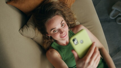 Positive lady speaking cellphone video call closeup. Relaxed woman laying sofa