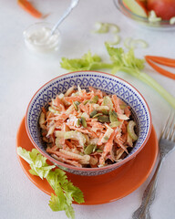 salad of grated carrots, apples and celery in a blue bowl, light background, no people, close-up