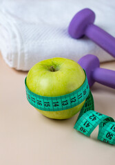 The concept of a healthy image, sports, nutrition, weight loss, fitness. Towel, dumbbells, bottle of water, measuring tape and green apples.