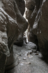 A narrow passage among steep cliffs in a mountain gorge. A swift mountain stream flows at the bottom of the gorge. Fascinating trekking in the mountain park of Saklikent Canyon.
