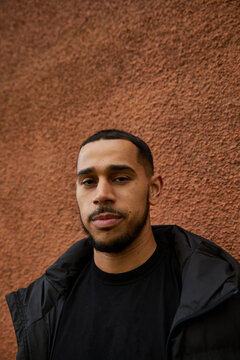 Portrait of a biracial man standing against a textured wall. Concept of multiracial family, motherhood, older parents and adult children.
