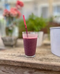 Focus on a fresh blended strawberry smoothie sitting on a wooden table with background blurred out.