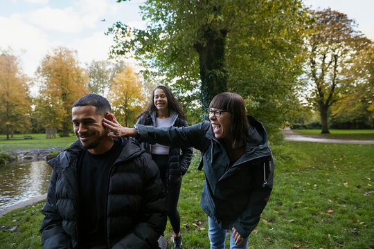 Mother being silly and lightly teasing her son during family walk. Concept of multiracial family, motherhood, older parents and adult children.