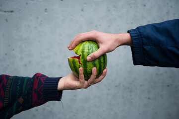 two hands people handing over a broken water melon