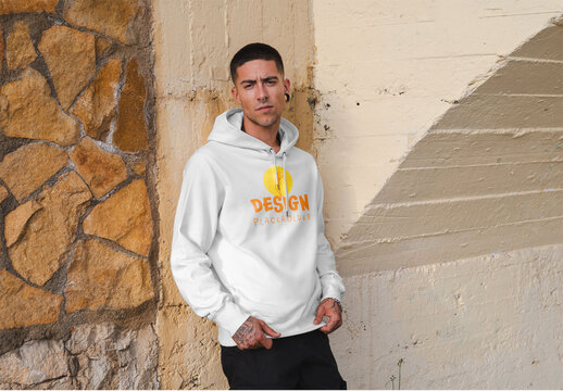 Mockup of man wearing hoodie with customizable color and design by wall